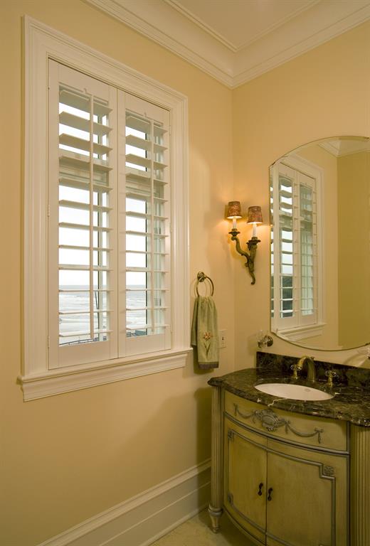 White plantation shutters in a bathroom give a view of the ocean